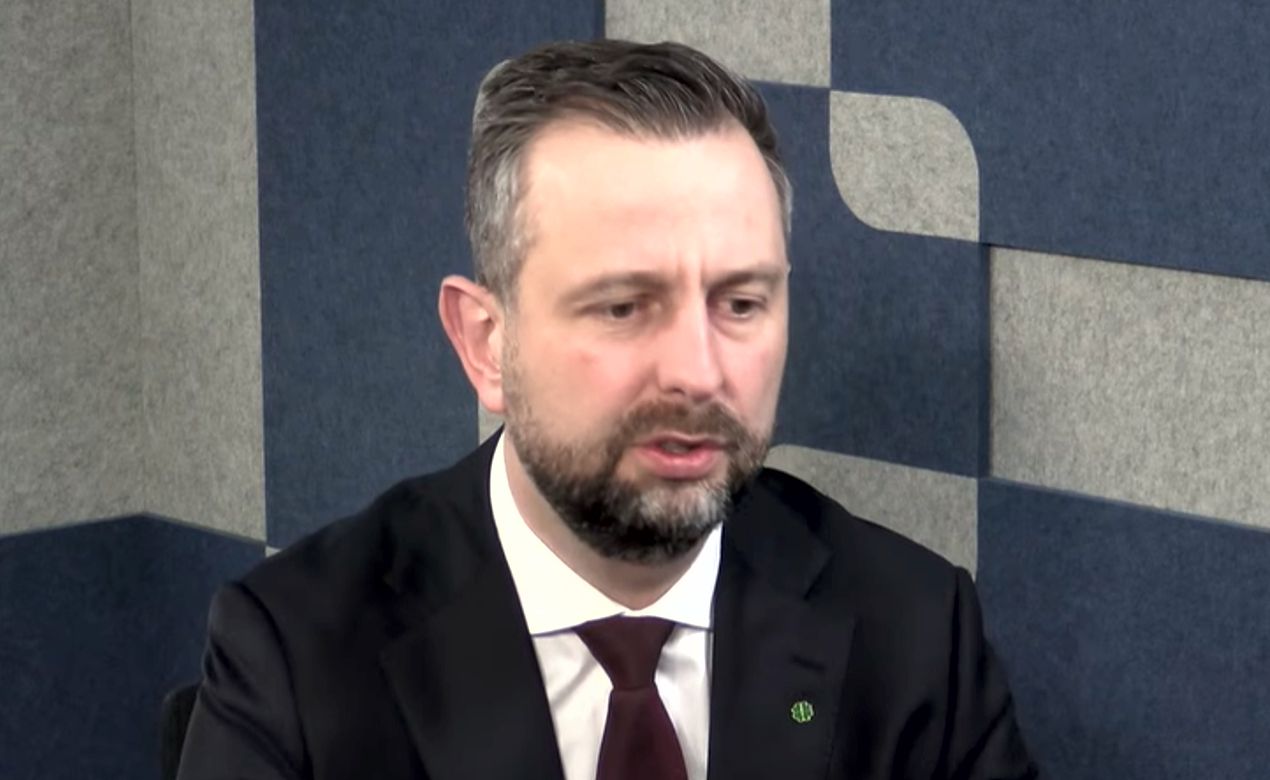 W kuluarach mówi się o nerwach, w oficjalnych wypowiedziach - o powadze państwa. Władysław Kosiniak-Kamysz przed nadchodzącym posiedzeniem Rady Bezpieczeństwa Narodowego postawił sprawę jasno: agenda ma znaczenie, a to, co do niej trafiło, wywołuje sprzeciw w rządzie.

Precedensowe uderzenie w Marszałka Sejmu. „Fakty bronią”

Szef MON w rozmowie z TOK FM skrytykował decyzję prezydenta o wpisaniu do porządku obrad punktu dotyczącego Włodzimierza Czarzastego. W ocenie wicepremiera ma to wyglądać jak próba użycia RBN do bieżącej walki politycznej.

Kosiniak-Kamysz podkreślił, że to sytuacja bez precedensu i uderzenie w powagę instytucji doradczej głowy państwa. Zapowiedział też, że jeśli zajdzie potrzeba, zabierze głos w obronie marszałka.

„Myślę, że fakty bronią marszałka Sejmu. Jeżeli trzeba będzie, to będę zabierał głos”.

W tej samej wypowiedzi wybrzmiewa jeszcze jedno: zdaniem ministra wyciąganie spraw prywatnych na forum poświęcone bezpieczeństwu i obronności ma być szkodliwe dla interesu publicznego.

Program SAFE jako kość niezgody. MON odpiera zarzuty opozycji

Drugim mocnym wątkiem posiedzenia ma być program SAFE. Kosiniak-Kamysz wskazał, że projekt dotyczy finansowania modernizacji armii i został opracowany podczas polskiej prezydencji w Unii Europejskiej.

Szef MON zdecydowanie odrzucił krytykę ze strony polityków Prawa i Sprawiedliwości, którzy - jak relacjonowano - przedstawiają program jako ryzykowny dług prowadzący do bankructwa resortu. Minister ocenił te oskarżenia jako polityczne.

„Przedstawiciele opozycji opowiadają bzdury”.

W jego ujęciu sprzeciw PiS ma wynikać z ideologicznej niechęci do Brukseli i chęci podważenia rozwiązań obecnego rządu, co - jak sugeruje - psuje debatę o bezpieczeństwie.

Kulisy oskarżeń o rosyjskie powiązania. Skąd wzięła się ta sprawa

Kontrowersje wokół marszałka Sejmu mają - według przywołanych informacji - źródło w publikacjach medialnych o rzekomych kontaktach biznesowych jego rodziny z obywatelką Rosji. Wskazano nazwisko Swietłany Czestnych, którą doniesienia łączą z instytucjami finansowymi kontrolowanymi przez Kreml.

Opisano też wątek powiązań kapitałowych w spółce hotelowej, w której zarządzie ma zasiadać żona polityka, a on sam ma posiadać udziały. To właśnie ten kontekst ma stać za politycznym napięciem i konsternacją po stronie rządowej, gdy temat trafił do agendy RBN.

Strategia wobec USA i „Rada Pokoju” Trumpa. Kosiniak-Kamysz uderza w opozycję

W rozmowie pojawił się także temat relacji ze Stanami Zjednoczonymi oraz tzw. Rady Pokoju Donalda Trumpa. Kosiniak-Kamysz krytycznie ocenił działania opozycji, uznając je za szkodliwe dla polskiej dyplomacji.

W jego wypowiedzi padło mocne sformułowanie o stylu zabiegania o względy Waszyngtonu.

„Chyba chęć nadmiernego nawet, służalczego podlizywania się, które jest niepotrzebne i nieoczekiwane”.

Według ministra Polska powinna stawiać na partnerskie relacje i konkretne projekty zbrojeniowe, zamiast demonstrować polityczną uległość. Jego zdaniem nadchodzące posiedzenie RBN pokaże, czy klasa polityczna jest w stanie wypracować wspólną linię w obliczu zmian międzynarodowych.